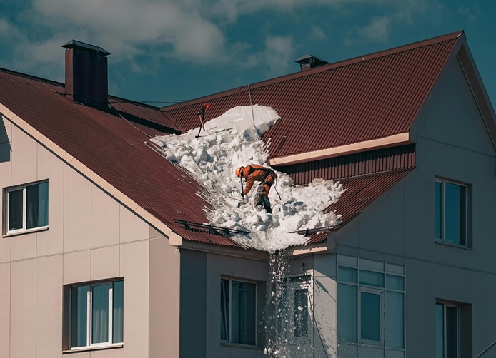 Roofers removing snow from a roof